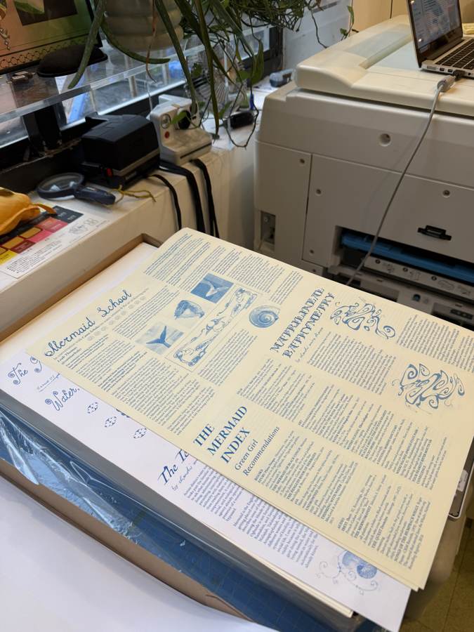 Issue 01 proofs at the printer: blue ink on cream stock, newspaper format.